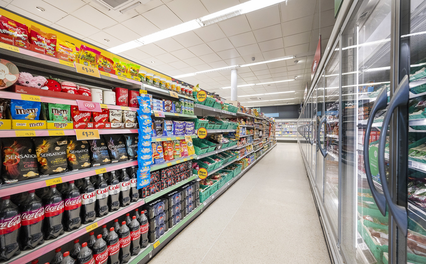 Supermarkt-Gang mit Regalen voller Snacks und Getränken.