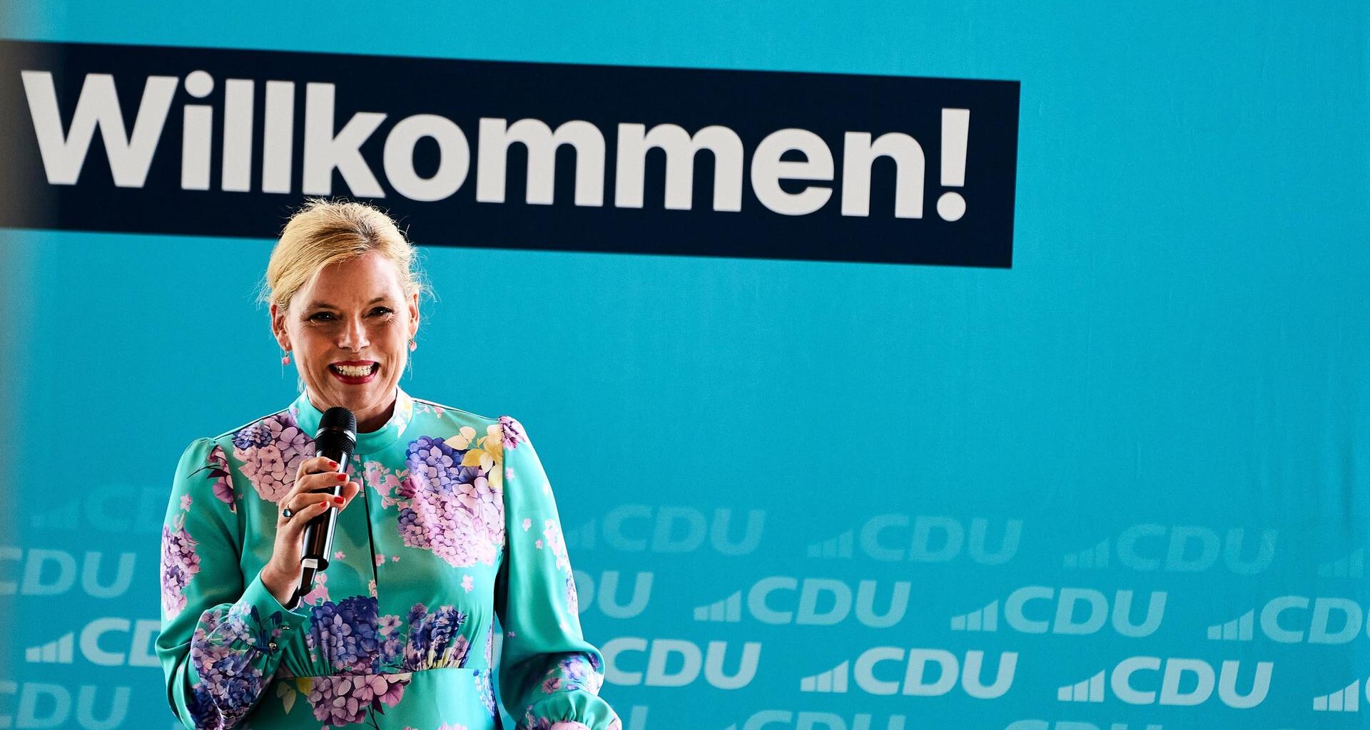 Bundestagspräsidentin Julia Klöckner (CDU) hält eine Rede beim CDU-Sommerfest in Koblenz. Sie trägt ein türkises Blumenkleid.