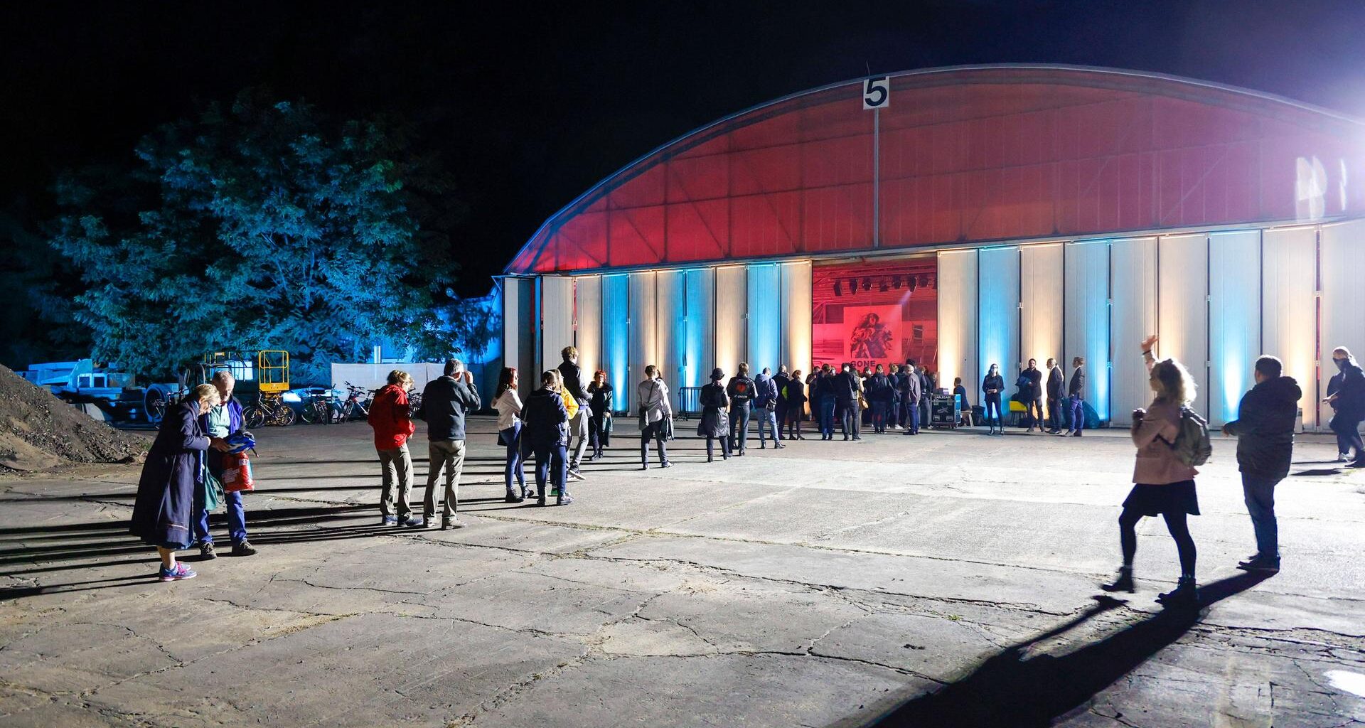 Menschen warten vor einer Halle auf Einlass.