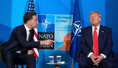 Mark Rutte wendet sich Donald Trump mit ausgstrecktem Zeigefinger zu. Im Hintergrund sieht man die NATO-Flagge.