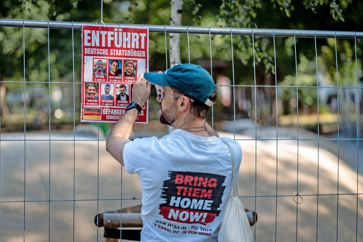 Protest am Bauzaun: Ein Kritiker des Camps hängt ein Plakat auf, um an israelische Entführte in Gaza zu erinnern.