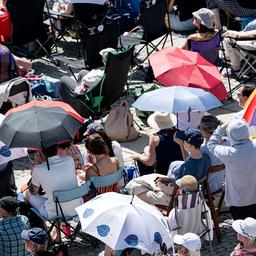 Menschen verfolgen mit Schirmen bei hohen Temperaturen das Open-Air Konzert der «Staatsoper für alle» (Quelle: dpa/Fabian Sommer)