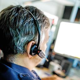 Symbolbild:Ein Polizist mit Headset sitzt an einem Computer.(Quelle:picture alliance/dpa/M.Balk)