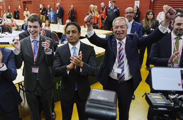 Der Vorsitzende von Reform UK, Nigel Farage (r.), jubelt vor Medienvertretern, nachdem die Reformkandidatin S. Pochin die Nachwahlen in Runcorn und Helsby gewonnen hat.
