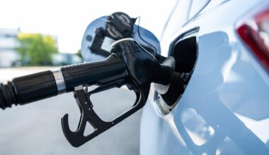 Ein Tankrüssel steckt während eines Tankvorgangs in einem Verbrenner an einer Zapfsäule einer Tankstelle.