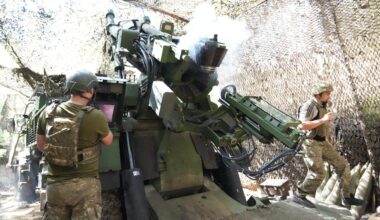 Soldaten feuern ein Artilleriegeschütz in einer getarnten Deckung ab.
