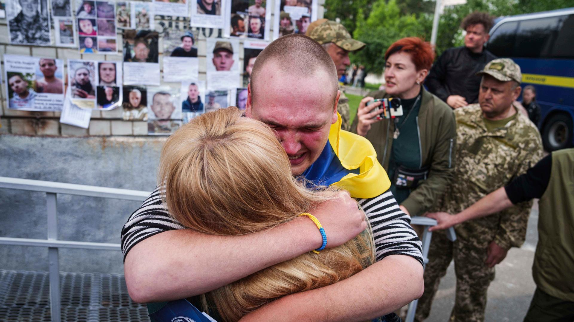 Ein ukrainischer Soldat weint und umarmt seine Mutter. Dahinter weitere Personen.
