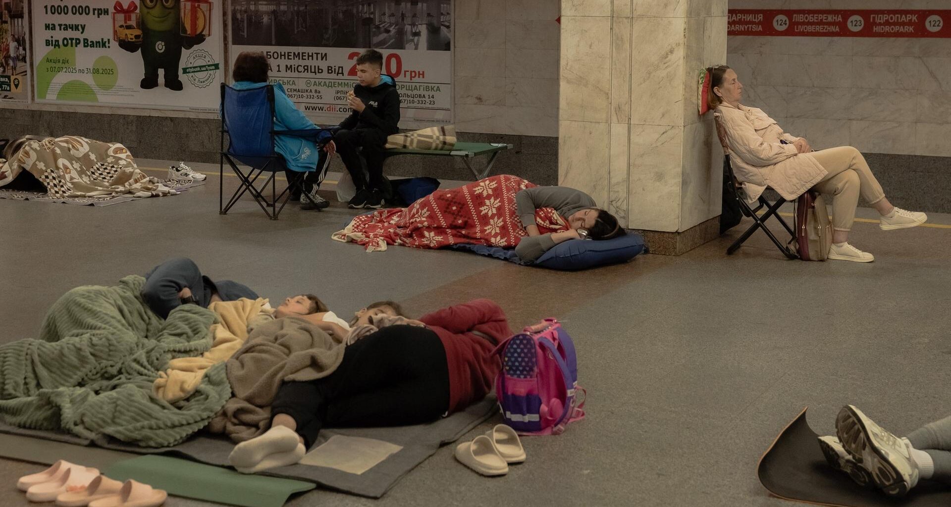 Menschen sitzen oder liegen in einer U-Bahn-Station in Kiew.