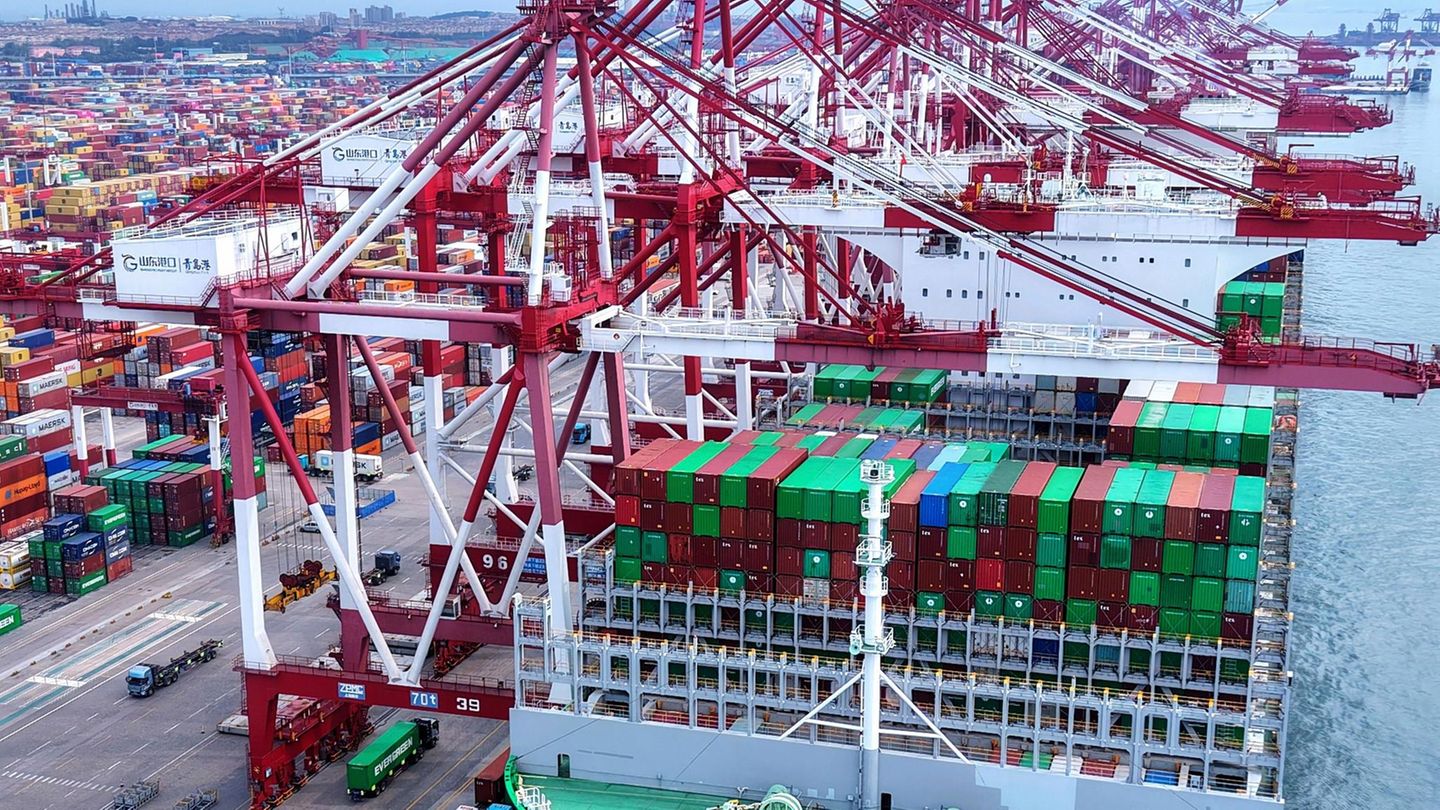 Lastwagen fahren an einem Schiff vorbei, das an einem Containerterminal in der ostchinesischen Provinz Shandong angedockt ist