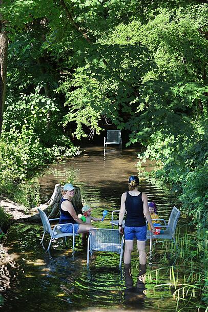 Das Freibadbächl fließt leise durch den Rosengarten. Im Sommer stehen die metallenen Stühle, die sonst am Weg oder auf der Wiese stehen, im Wasser – hervorragend, um die Füße abzukühlen und mit den Kindern zu planschen.
