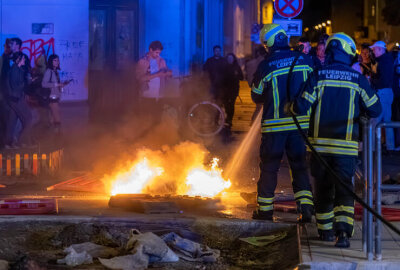 Brennende Barrikaden am Karli sorgen für Aufregung - Flammen lodern auf der Straße – Feuerwehrleute löschen die brennenden Reste. Foto: EHL Media