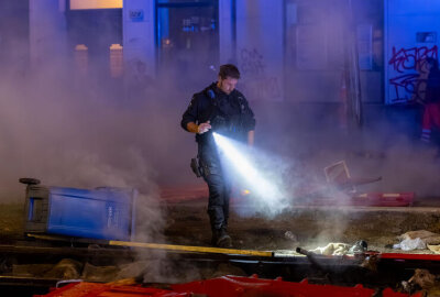 Brennende Barrikaden am Karli sorgen für Aufregung - Ein Polizist durchsucht die qualmenden Überreste mit Taschenlampe nach weiteren Brandherden. Foto: EHL Media
