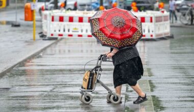 Eine Frau mit Rollator und Regenschirm geht am 15.07.2025 im Regen über den Berliner Hardenbergplatz. (Quelle: dpa-Bildfunk/Soeren Stache)