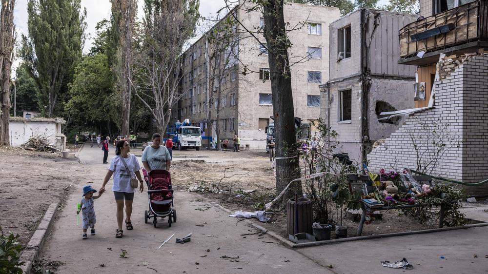 Sanktionen gegen Russland: Menschen laufen an einem zerstörten Haus in Kyjiw vorbei: Die Weltbank rechnet mit 500 Milliarden Euro Kosten für den Wiederaufbau in der Ukraine.