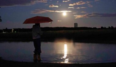 Symbolbild:Ein Kind steht am Abend am mit einem roten Regenschirm in einer Pfütze auf dem Tempelhofer Feld und beobachtet den Vollmond. (Quelle:picture alliance/dpa/C.Koall)