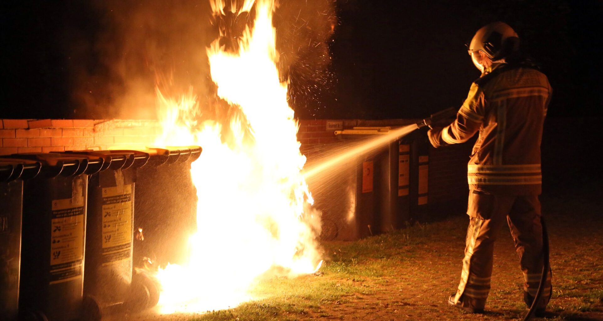 Ein Feuerwehrmann löscht einen brennenden Müllcontainer. Symbolbild - Foto: Roland Halkasch