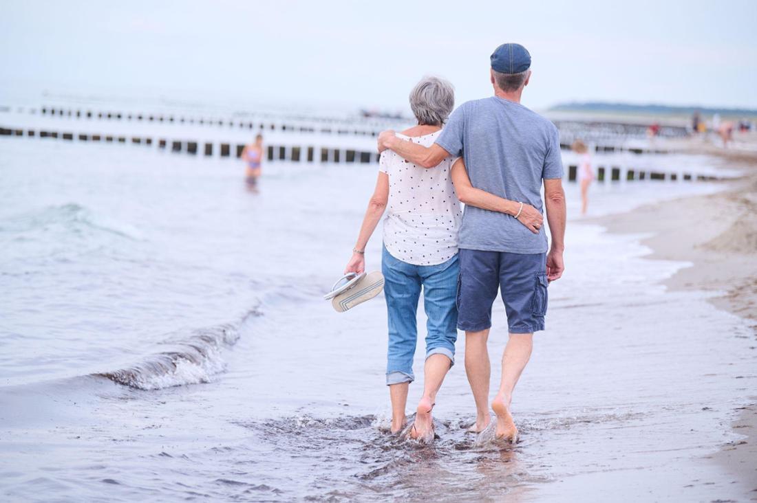 Ein Rentner-Paar spaziert am Strand entlang