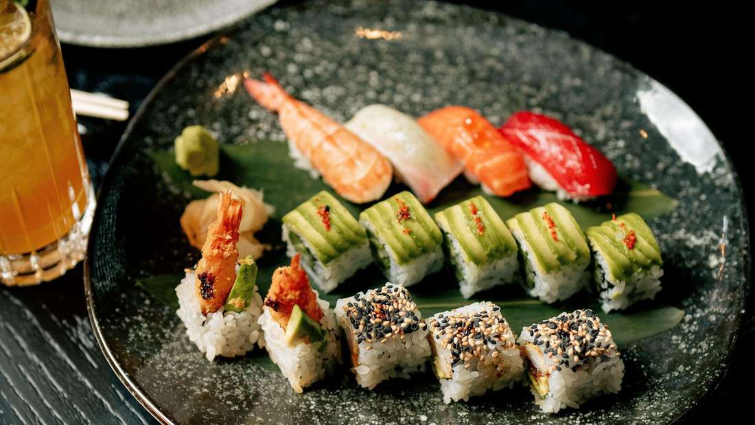 Auf einem schwarzen Teller ist Sushi künstlerisch drapiert
