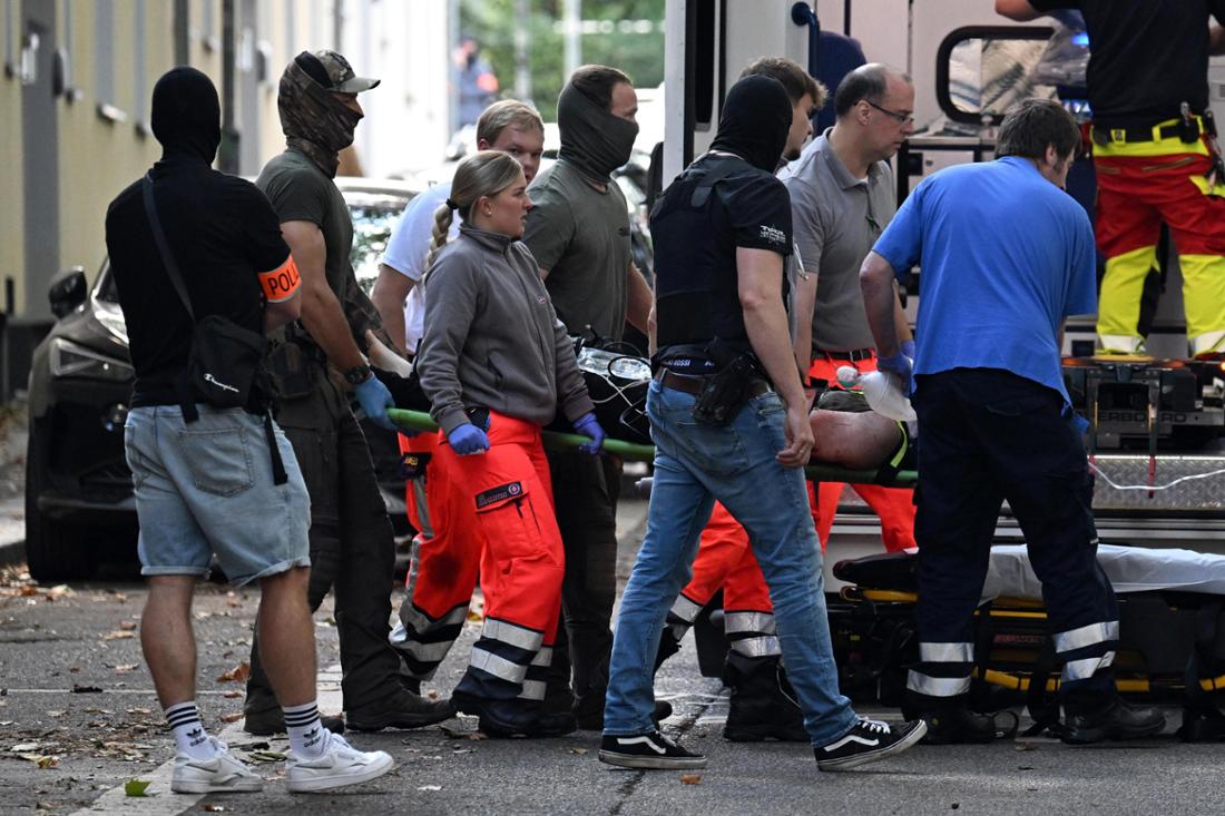 Einsatzkräfte bringen die Trage mit einer verletzten, tatverdächtigen Person zu einem Rettungswagen. 