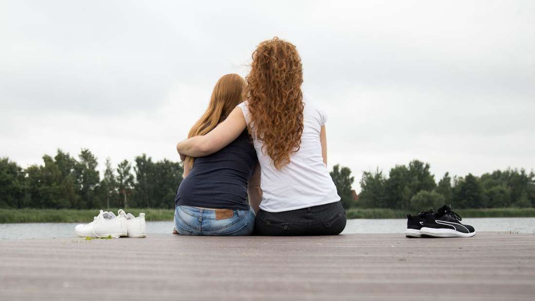 Zwei Frauen sitzen auf einem Steg am See