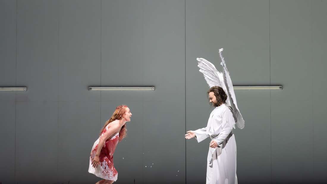 Die Sängerin und der Sänger stehen einander vor weißer Wand gegenüber.