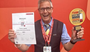 Mann hält freudestrahlend Urkunde und Pokal in die Kamera.