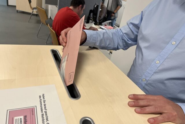 Ein Mann wirft einen Brief in eine Wahlurne