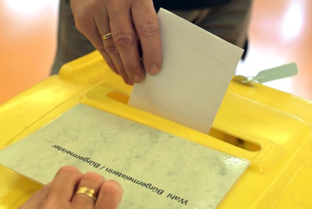 Ein Wähler steckt einen Wahlzettel in eine Wahlurne.