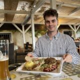 Ein junger Mann sitzt im Biergarten des Restaurants „Von Herzen“ in Lütgendortmund und hält einen gefüllten Teller in die Kamera.