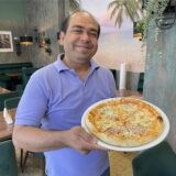 Gastronom Muhammad Irfan steht in seinem Lokal in Lütgendortmund und hält eine Pizza-Teller in der Hand.