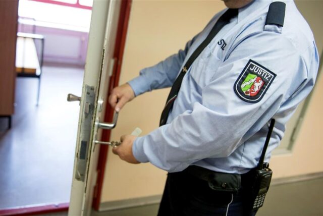 Ein Polizist schließt eine Tür auf.