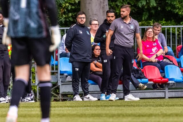 Ein Trainer steht stabil an der Seitenlinie.