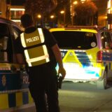 Ein Polizist lehnt auf der Kampstraße in der Dortmunder Innenstadt an ein Polizeiauto.