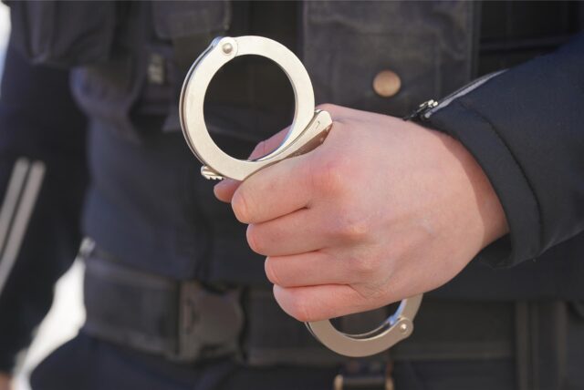 Ein Polizist hält Handschellen in der Hand. (Symbolbild)
