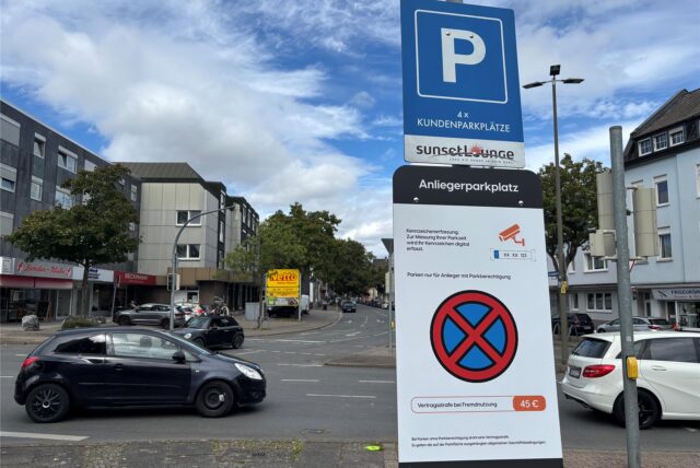 Auf dem Foto ist ein Parkplatzschild zu sehen, das auf Kundenparkplätze und Anliegerparkplätze hinweist. Auf dem Schild wird darauf hingewiesen, dass das Parken ohne Parkberechtigung eine Vertragsstrafe nach sich zieht und die Kennzeichen digital erfasst werden.