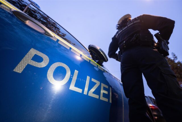 Ein Polizist steht vor einem Auto.
