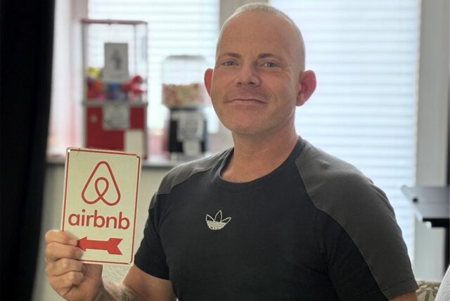 Tim mit eienm AirBnB-Schild in der Hand