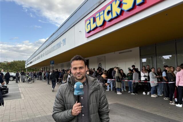 Reporter Martin Bytomski steht vor der Schlange am „Glückspilz“ im Indupark Dortmund.