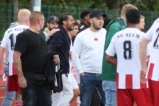 Spieler und Verantwortliche der SG Selm und des IKSV Münster stehen sich gegenüber.