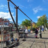 Besucher des Wochenmarktes in Lütgendortmund laufen am Samstag (13.9.) unter einer Baustelle her, bei der Wasserrohrleitungen weit in die Höhe verlegt wurden.