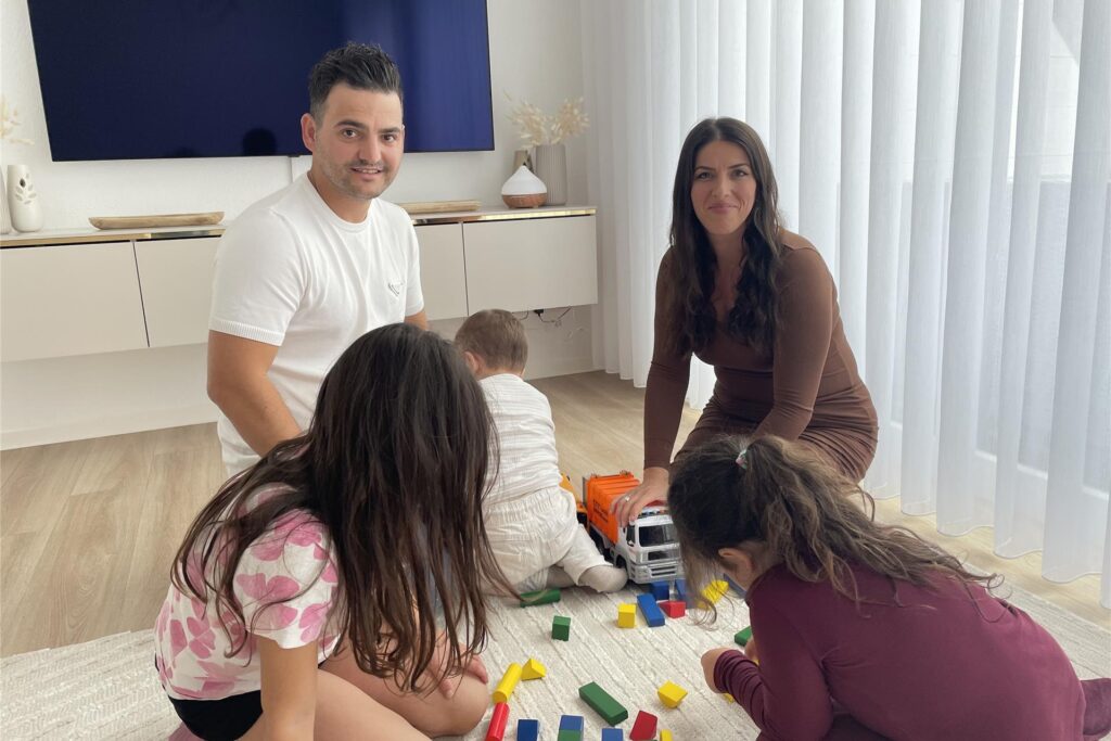 Eine Familie sitzt auf dem Boden und spielt mit ihren Kindern in Dortmund-Rahm.