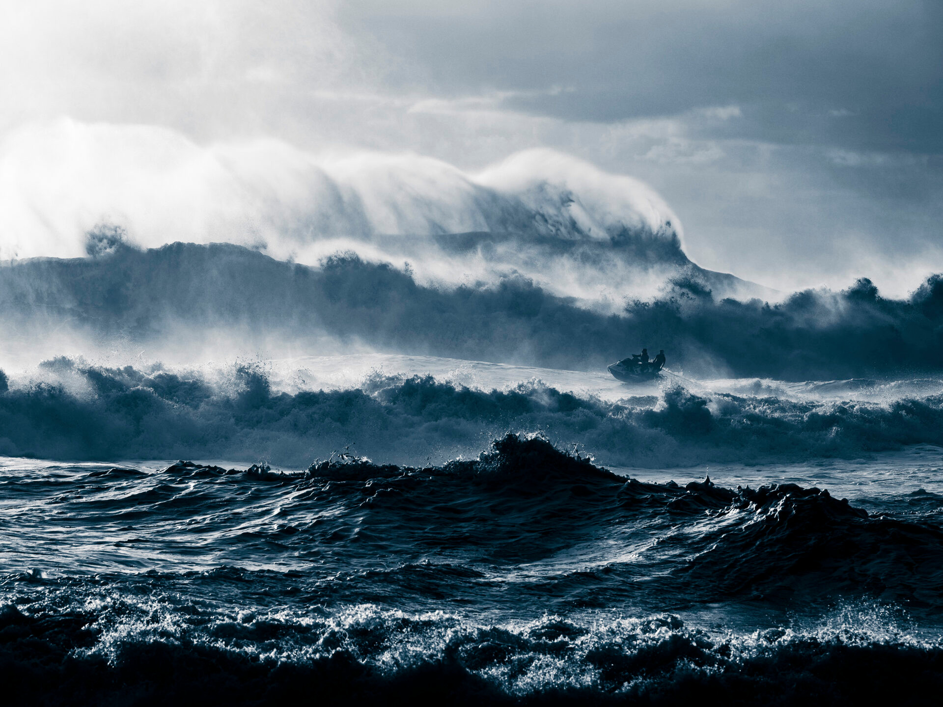 Stürmische See mit hohen Wellen und einem kleinen Boot im Hintergrund unter dramatischem Himmel.