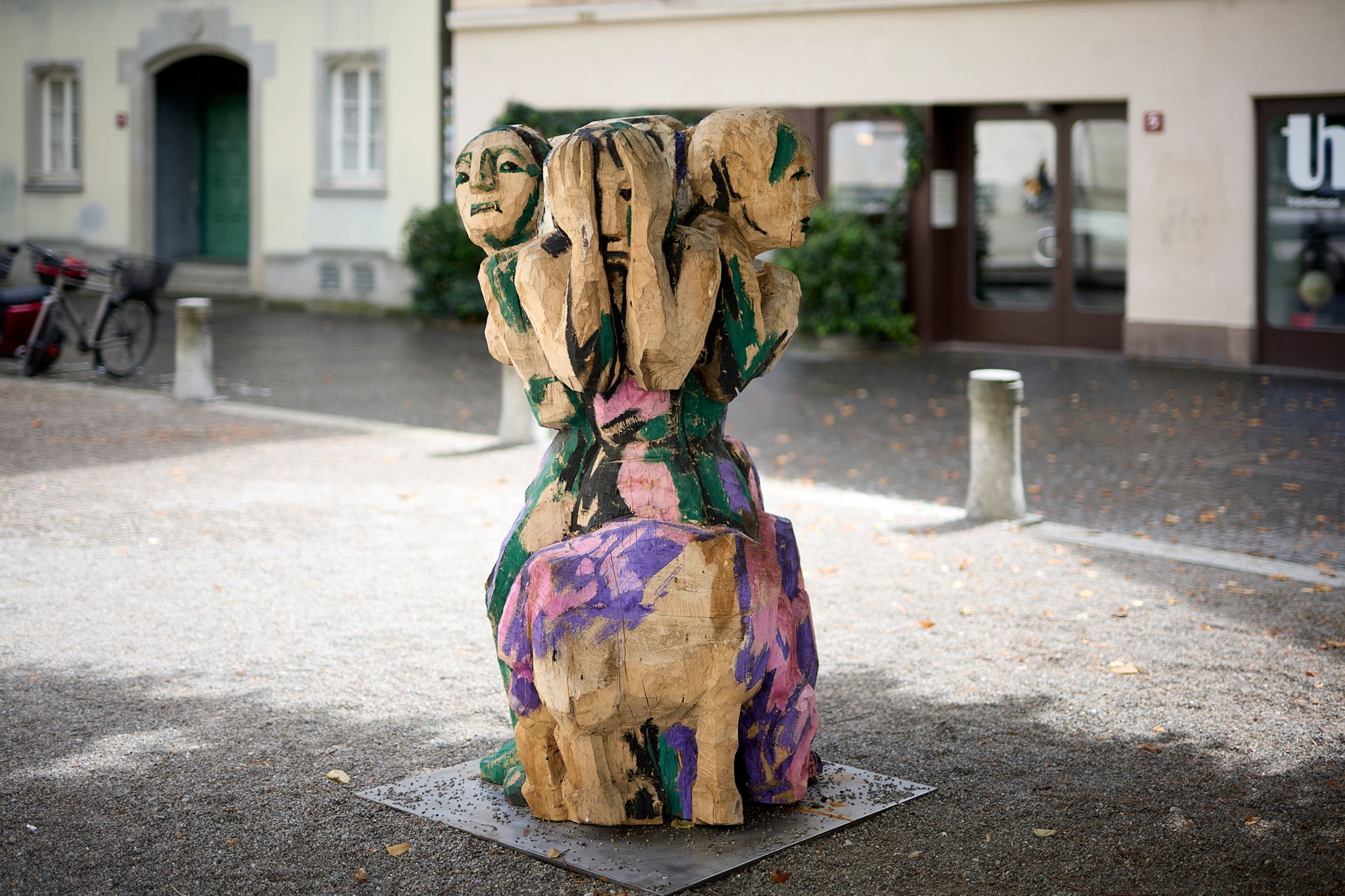 Holzskulptur ’Bedrängtes Tal’ von Werner Ignaz Jans auf einem Platz in Winterthur, zeigt ineinander verschlungene Figuren, bunt bemalt.