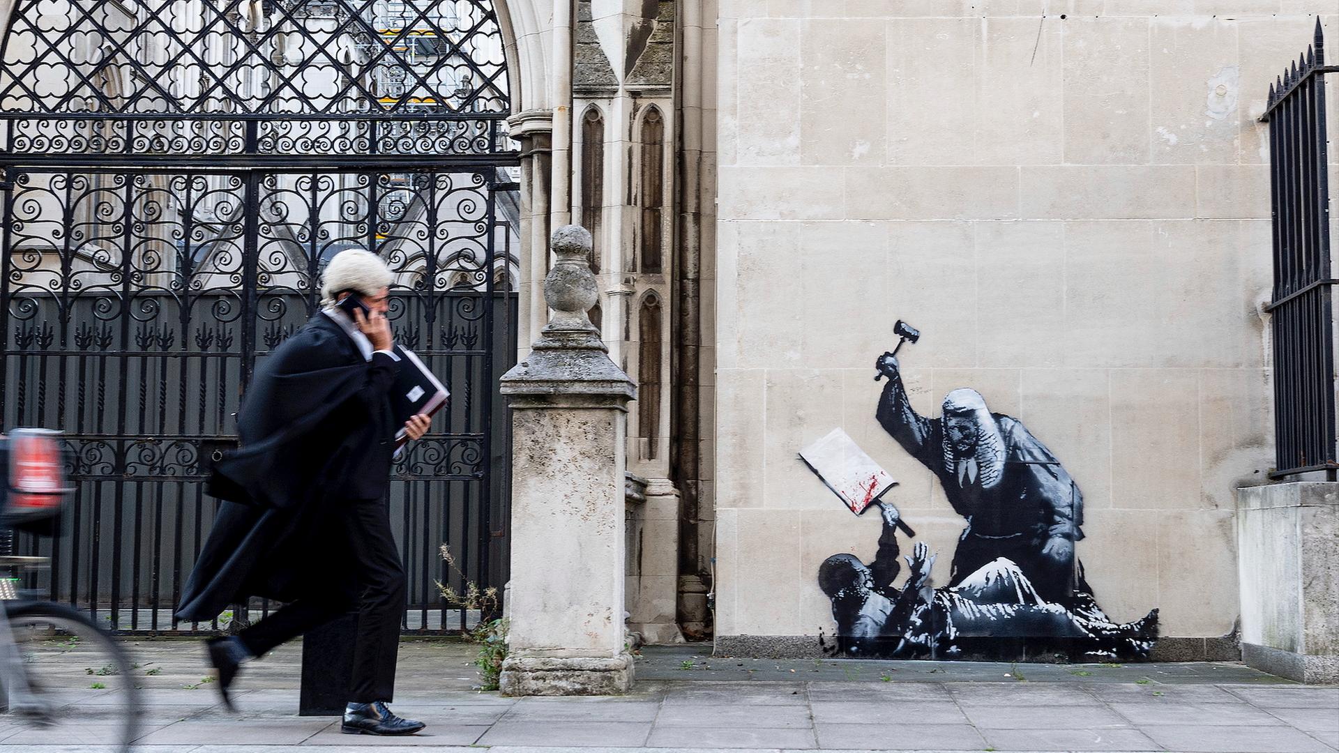 Das Foto zeigt ein Kunstwerk von Banksy. Zu sehen ist ein Richter, der einen Demonstranten im Royal Courts of Justice in London mit einem Hammer schlägt.
