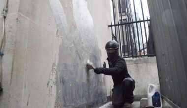Eine Person schrubbt das neueste Kunstwerk des britischen Künstlers Banksy an den Royal Courts of Justice ab