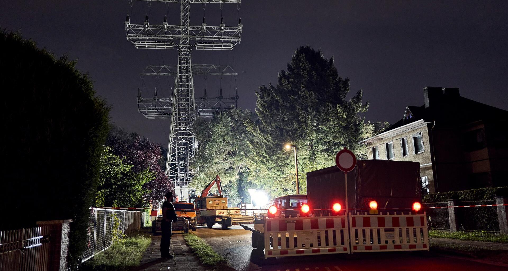 Bagger sind nachts vor einem Strommast im Einsatz.