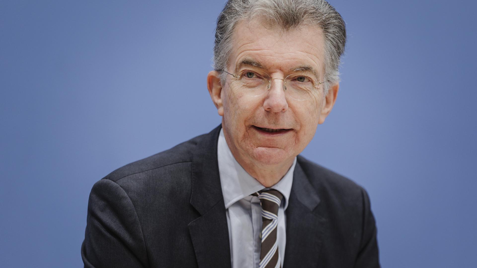 Christoph Heusgen, Politikberater; er trägt ein schwarzes Jackett, Hemd und Krawatte und sitzt vor einer bläulichen Wand.