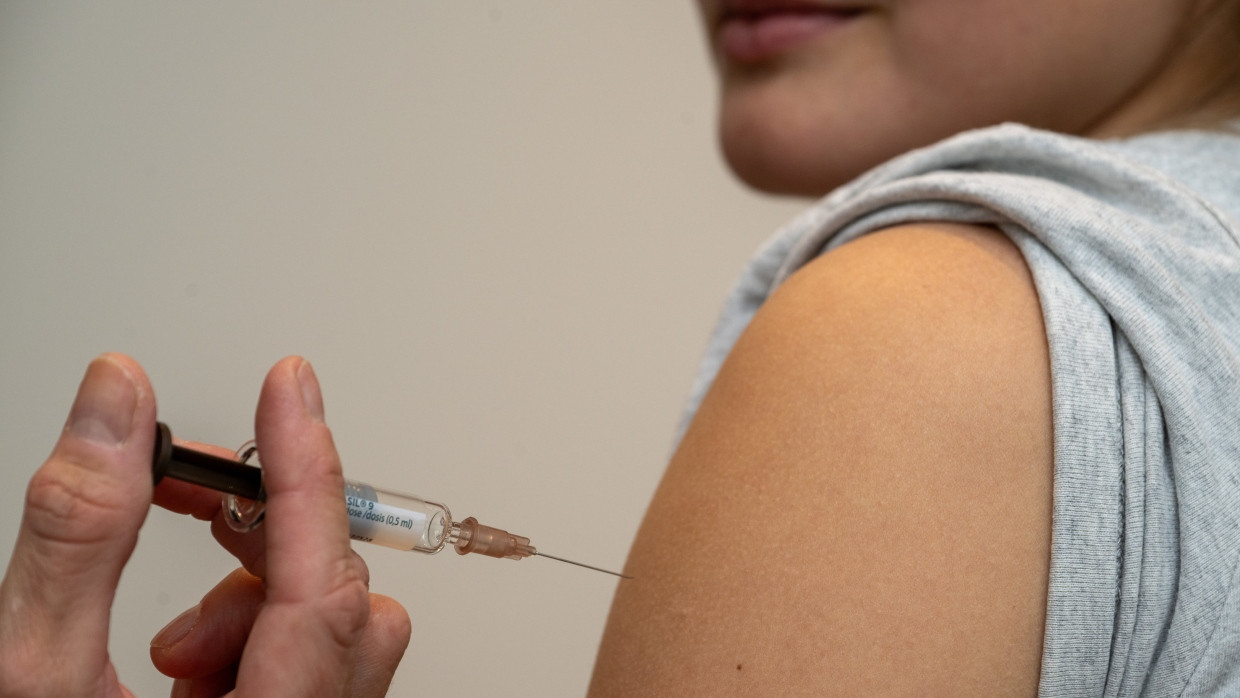 Eine Gynäkologin setzt bei der HPV-Impfung in einer Frauenarztpraxis eine Injektion in den Oberarm einer Jugendlichen.