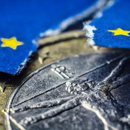 Eine Euro-Münze und eine zerrissene EU-Fahne