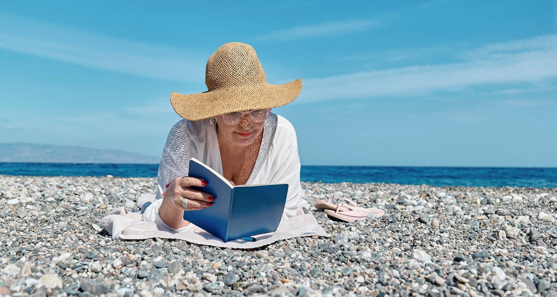 Eine Frau liest ein Buch an einem Strand